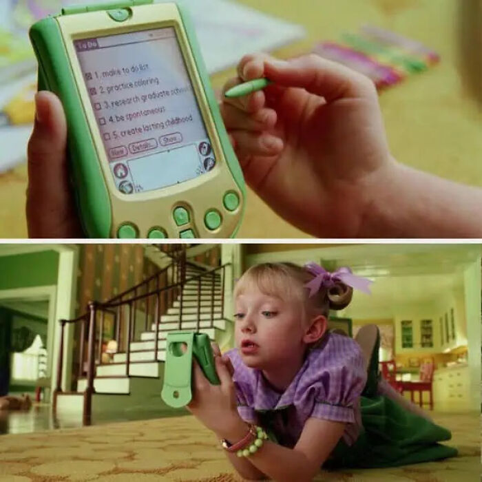 A hand holding a green electronic toy organizer, a movie prop used by a child actress laying down