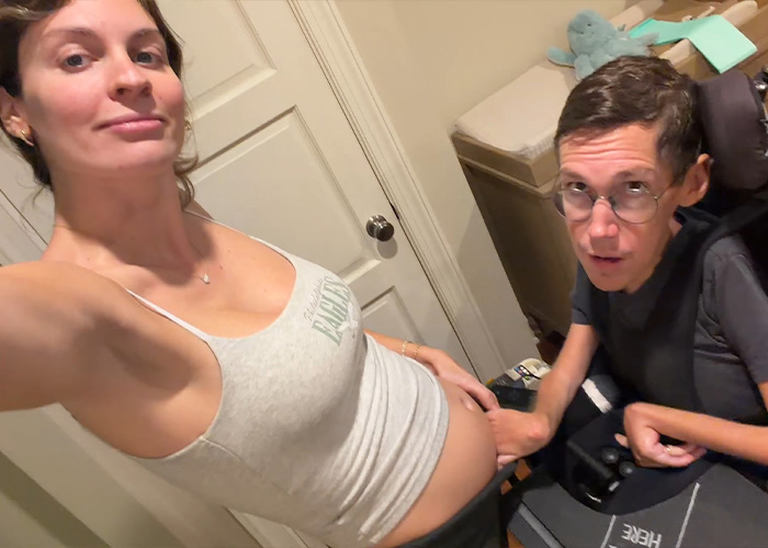 Interabled couple looking at the camera as the husband touches her pregnant belly Interabled couple looking at the camera as the husband touches her pregnant belly