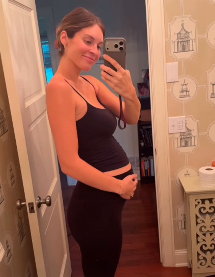 Smiling pregnant woman showing her baby bump in a mirror selfie Smiling pregnant woman showing her baby bump in a mirror selfie
