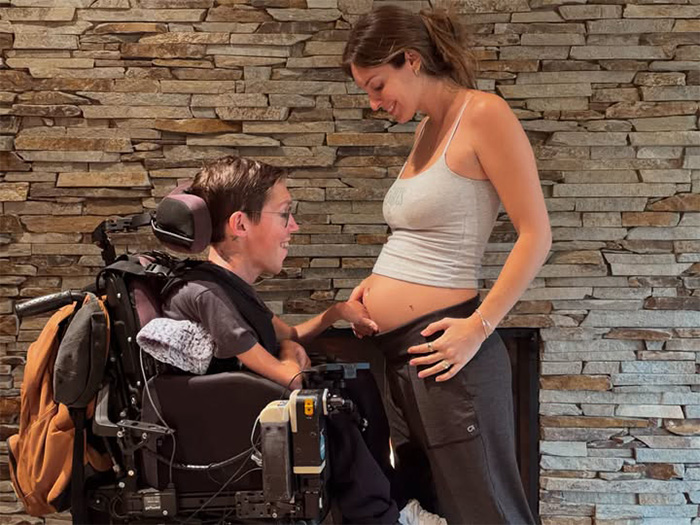 Interabled couple smiling as the husband in a wheelchair gently touches his pregnant wife's stomach. Interabled couple smiling as the husband in a wheelchair gently touches his pregnant wife's stomach.
