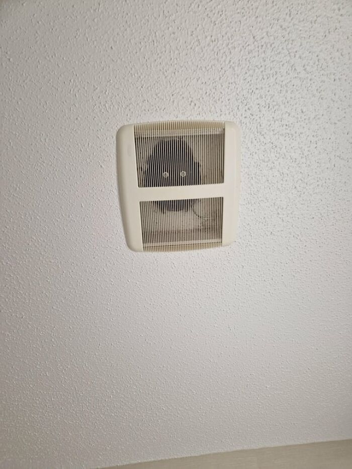 A weird and creepy photo of glowing eyes peering out from inside a ceiling air vent.