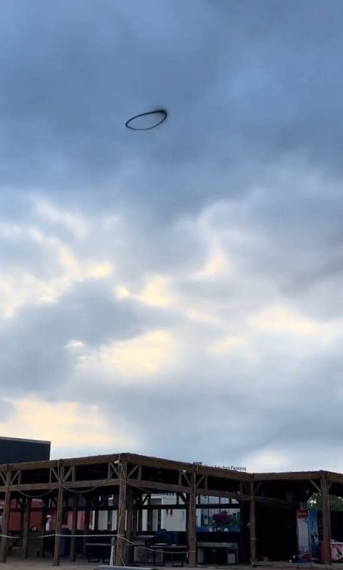 A strange black smoke ring floating above a building, making for a weird and creepy photo.