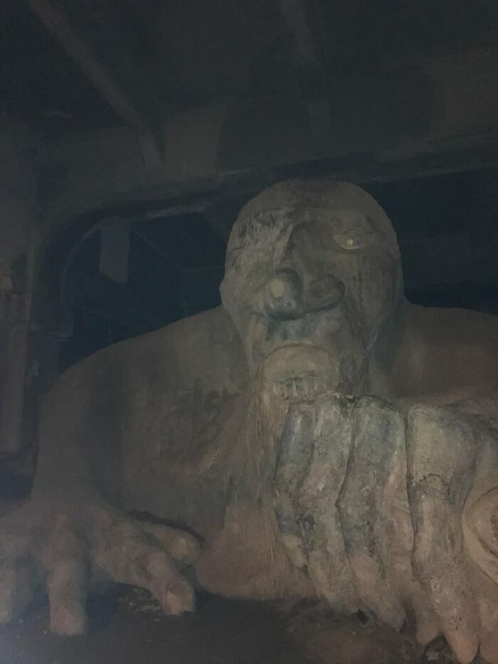 A giant stone troll sculpture lurking in dark room featured in creepy photos
