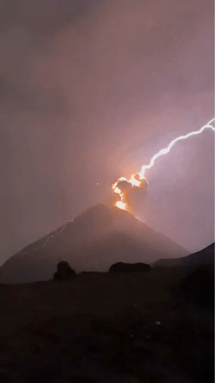 A lightning bolt striking the top of an erupting volcano at night, among creepy photos of nature.