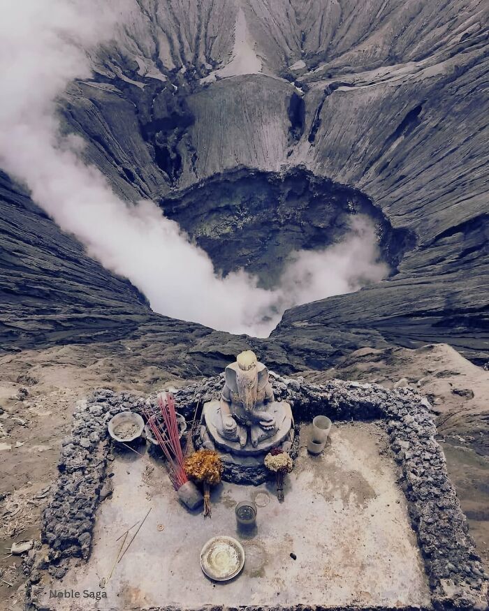 A small shrine at the edge of a smoking volcanic crater in a weird photo