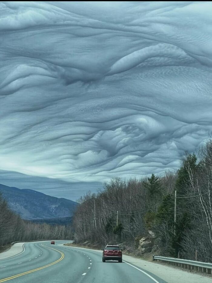 Dramatic wavy asperitas clouds rolling over a highway in creepy photos.