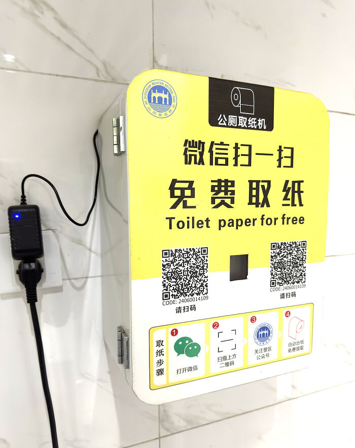 Absurd public toilet paper dispenser that requires scanning a QR code to unlock paper.