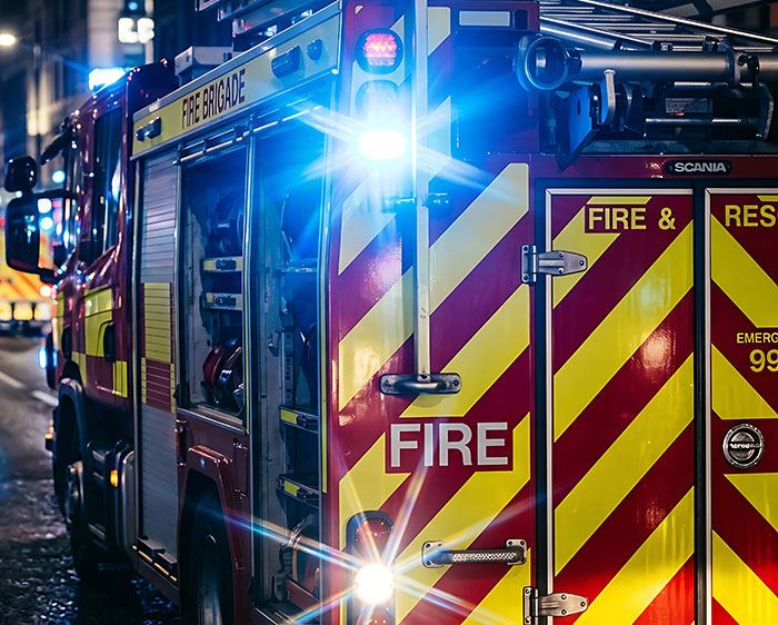 A red fire engine with bright flashing lights responds to a worst-case scenario emergency.
