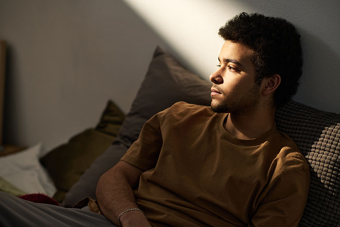 Pensive young man sitting indoors contemplating a worst-case scenario