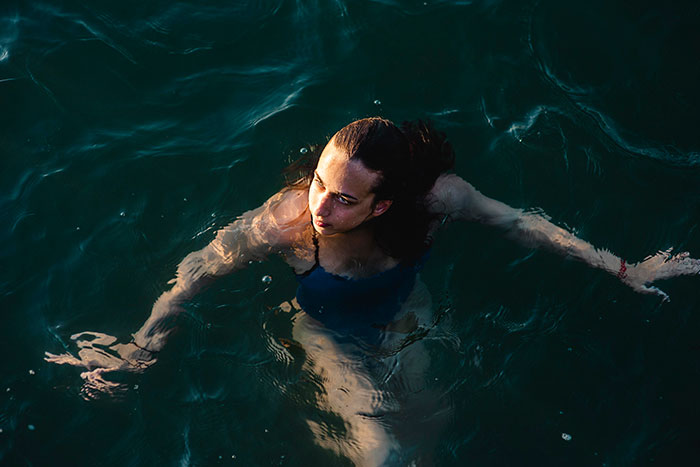Woman swimming alone in dark deep open water facing worst-case scenario