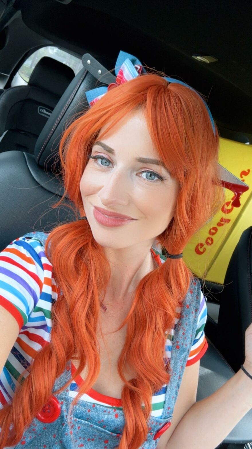 A woman with orange pigtails dressed in a Chucky-inspired outfit as a creative Halloween costume idea.