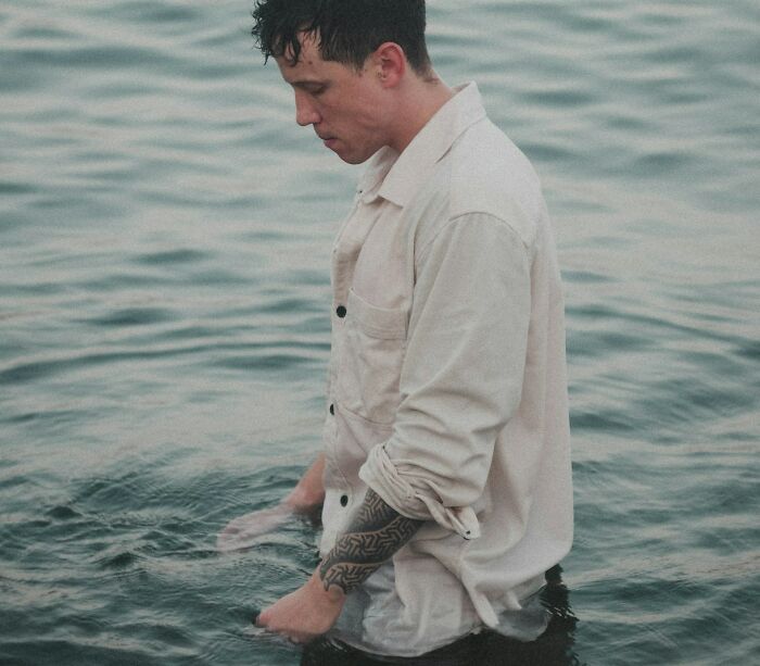 Man standing waist deep in water wearing white shirt