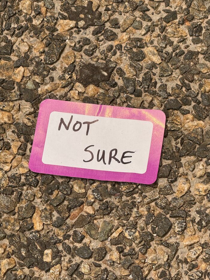 Found paper sticker on coarse stone ground reading NOT SURE