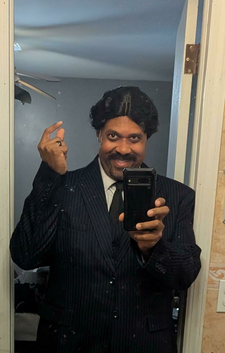 Man taking a mirror selfie wearing a pinstripe suit and wig as a creative Halloween costume idea.