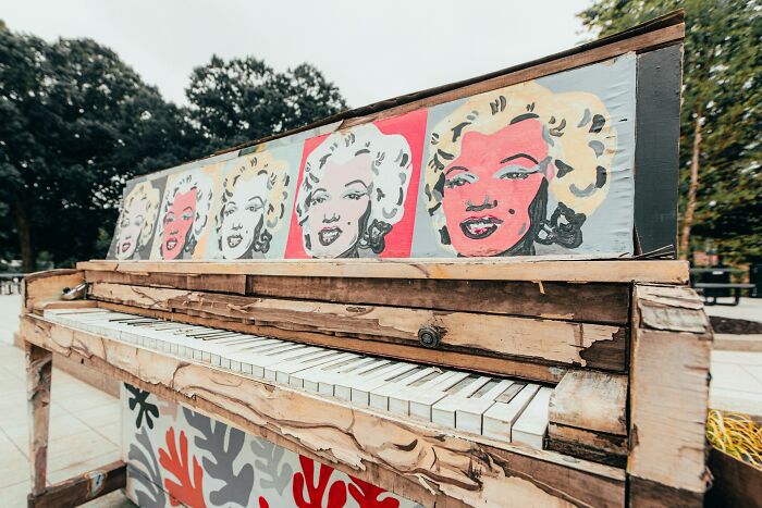 Worn piano decorated with Marilyn Monroe pop art paintings outdoors
