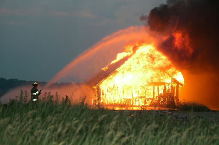 Firefighter spraying water on burning house during fire