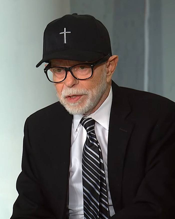 Televangelist Jim Bakker wearing a black cap with a cross and a suit during a television appearance. Televangelist Jim Bakker wearing a black cap with a cross and a suit during a television appearance.