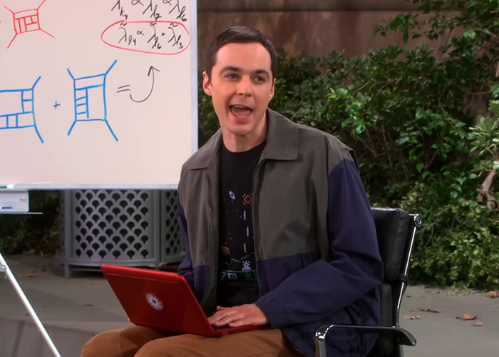 Jim Parsons sitting in a chair with a red laptop near a whiteboard discussing Young Sheldon. Jim Parsons sitting in a chair with a red laptop near a whiteboard discussing Young Sheldon.