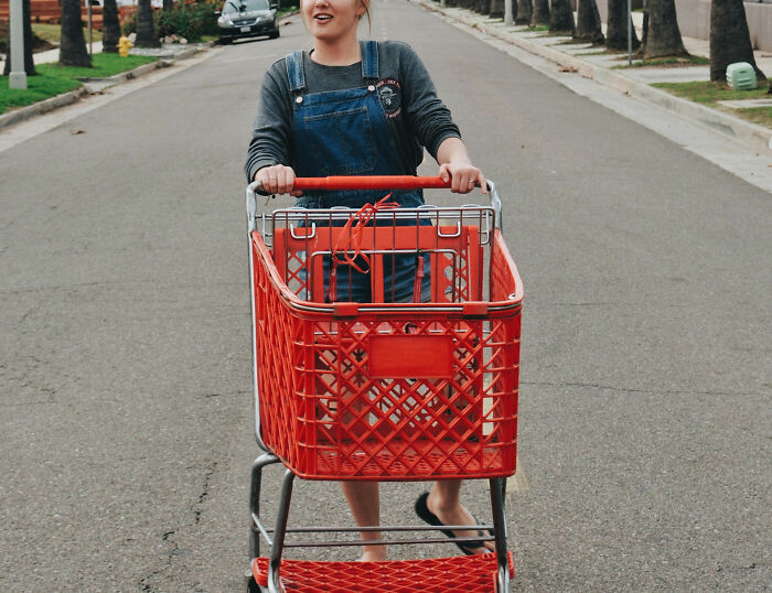 Young woman pushing shopping cart in quiet street, referencing Karen stories