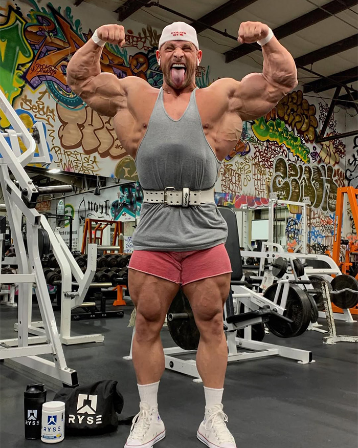 Fitness influencer Joey Swoll flexing his biceps and leg muscles inside a graffiti-filled gym Fitness influencer Joey Swoll flexing his biceps and leg muscles inside a graffiti-filled gym