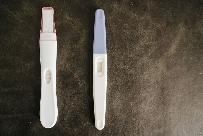 Two positive pregnancy tests lying on a dark surface, reflecting moments involving narcissistic parents.