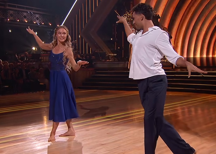 Hollywood actress and dance partner posing mid-dance on stage during a reality show performance.