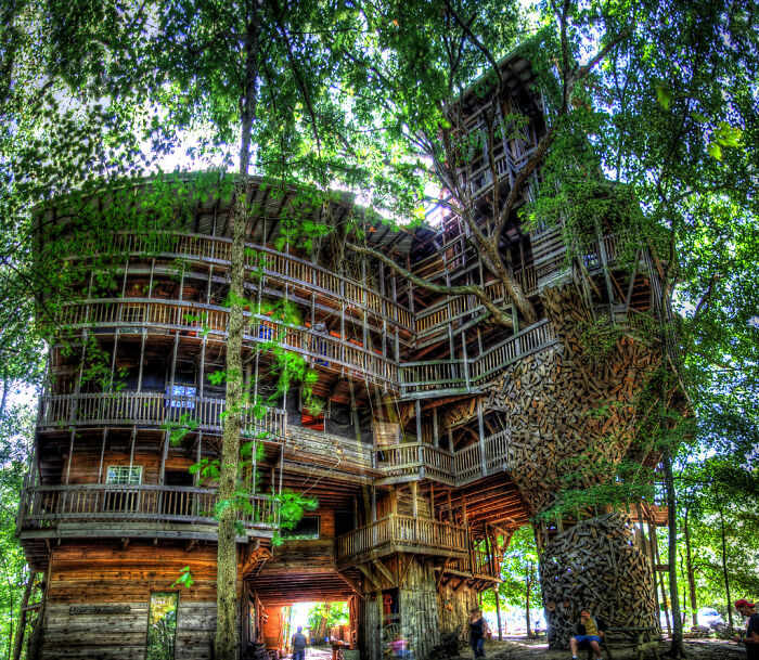 Large multi-level wooden treehouse with intricate design among trees