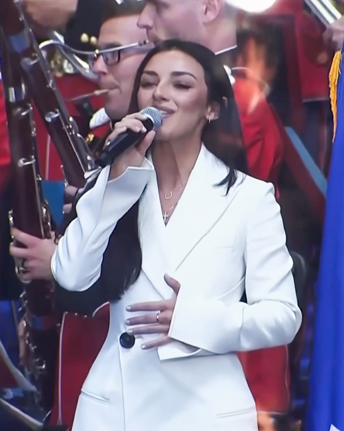 Kash Patel fiance&eacute; singing into a microphone in a white suit