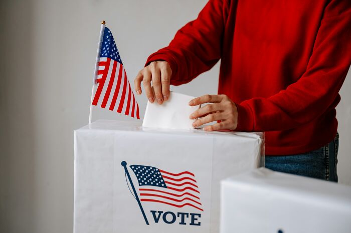 A voter placing a ballot in a box with US flags, illustrating impactful PR stunts in politics.