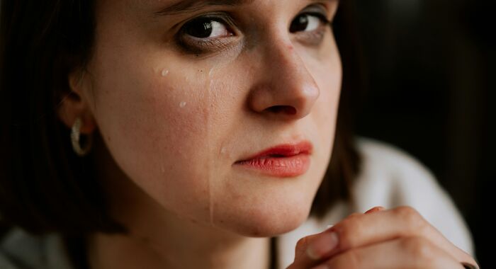 A close-up of a young woman crying with tears on her cheek, showing emotional impact from narcissistic parents.