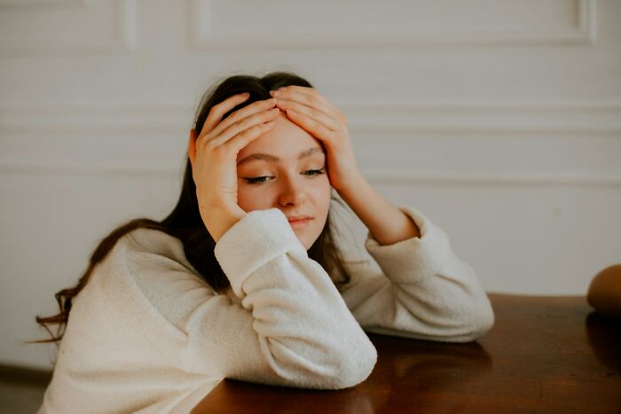 Woman holding her head in her hands after a funny instance of an embarrassing mistake.
