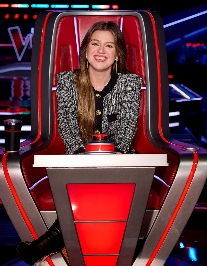Singer Kelly Clarkson sitting in the iconic red coach chair on set.