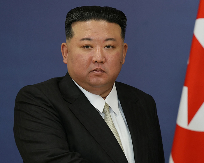 Portrait of Kim Jong Un in a suit next to the North Korea flag. Portrait of Kim Jong Un in a suit next to the North Korea flag.