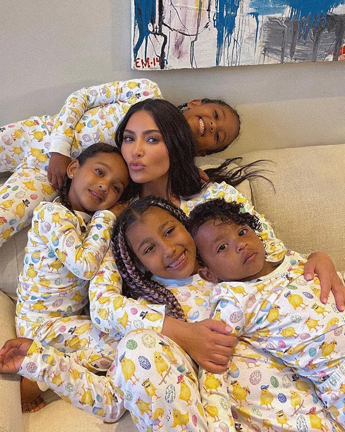 Kim Kardashian and her 4 kids wearing matching chick pajamas while hugging on a sofa Kim Kardashian and her 4 kids wearing matching chick pajamas while hugging on a sofa