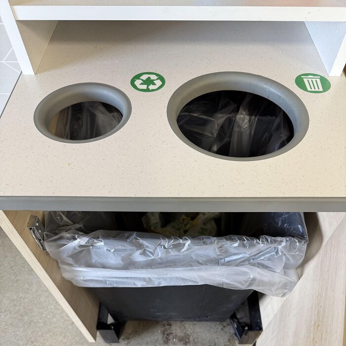 A dual trash and recycling cabinet leading to the exact same bin, one of many absurd signs and moments.