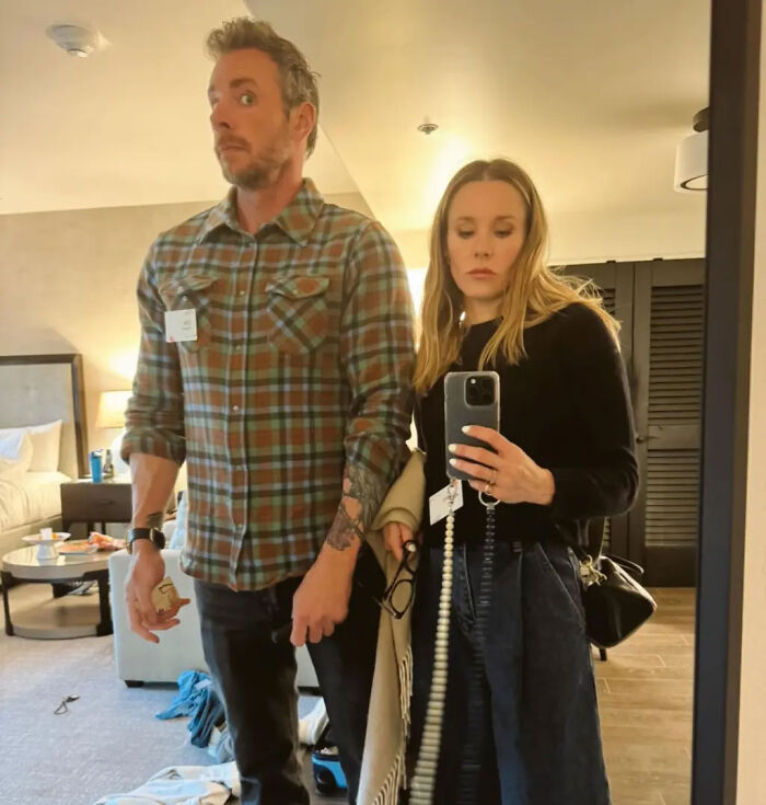 Kristen Bell taking a mirror selfie indoors next to Dax Shepard.