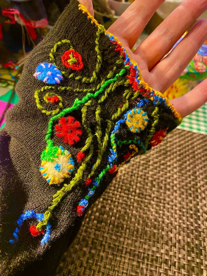 A black sleeve decorated with colorful embroidery, showing how creativity can save money on clothing repairs.