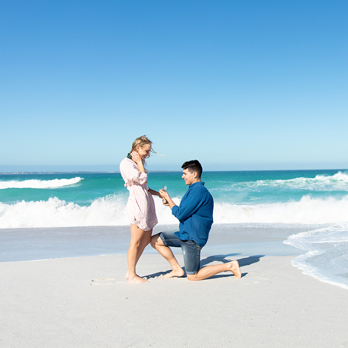 A couple having a romantic proposal on a beach by the ocean A couple having a romantic proposal on a beach by the ocean