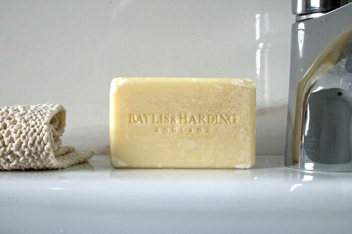 Bar of Baylis and Harding soap on bathroom sink with faucet and cloth