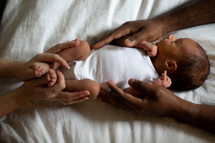A newborn baby held gently by parents, symbolizing family dynamics amidst painful infidelity stories.