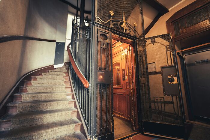 Old vintage elevator door open near spiral staircase depicting scary historical building moments