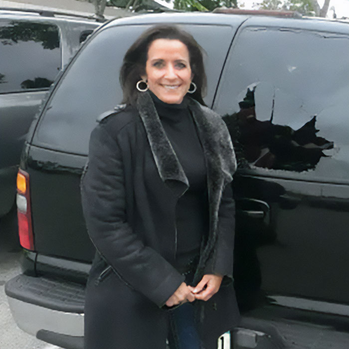 Woman in a black coat standing by a car, identified as the Karen who disrupted a Laguna Beach proposal.