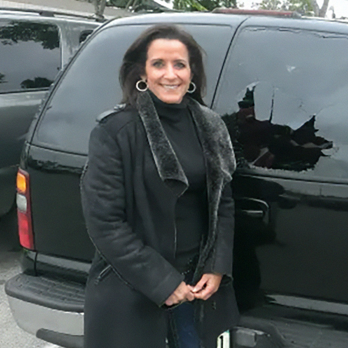 A woman identified as the Laguna Beach Karen smiling in front of a black SUV A woman identified as the Laguna Beach Karen smiling in front of a black SUV
