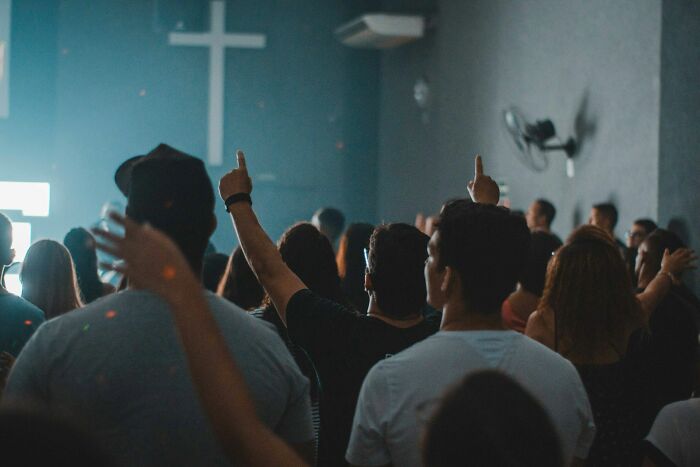 A crowd of people with raised hands gathered during a service connected to lesser-known cults.