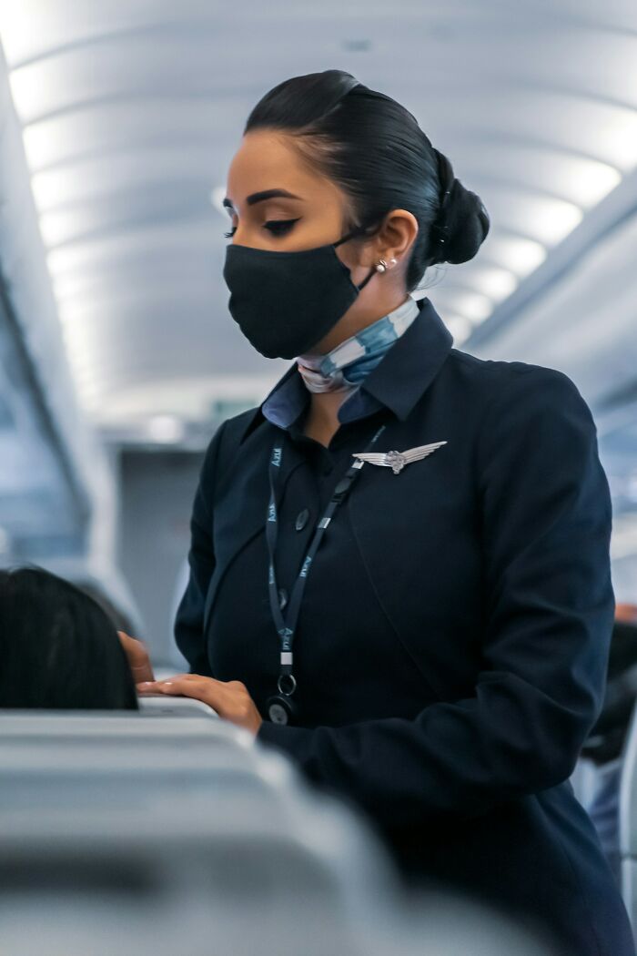 A flight attendant in a face mask assisting passengers on flights.