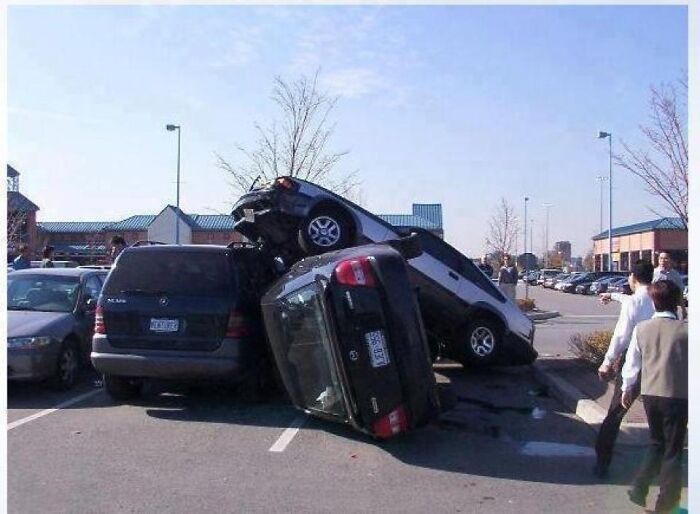An absurd accident where multiple cars are stacked on top of each other in a parking lot.