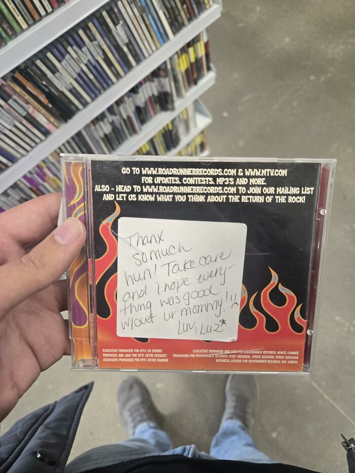 Person holding a CD case with a handwritten sticky note on the back, showing a found paper message