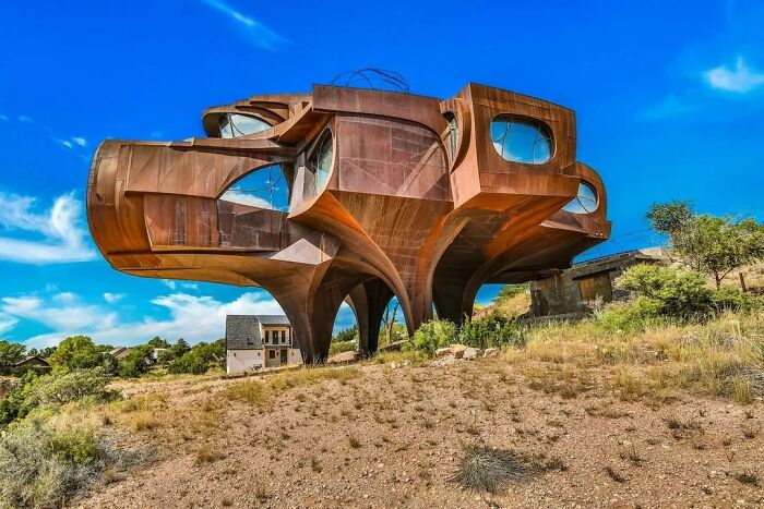 Futuristic strange building with curved metal structure on hillside