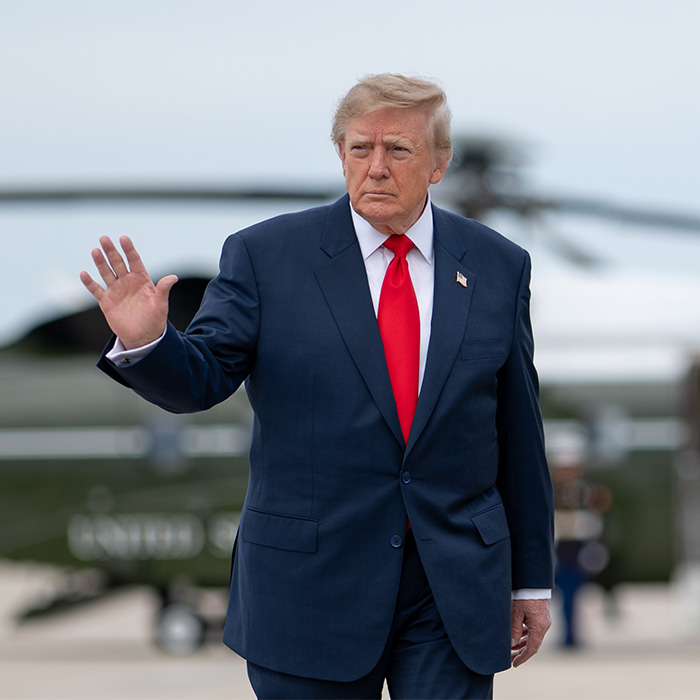 Donald Trump in suit waving with helicopter in background Donald Trump in suit waving with helicopter in background