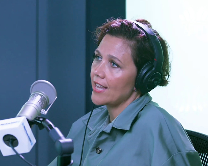 Hollywood actress wearing headphones and speaking into a microphone in a studio set up.